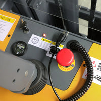 Close-up of a machine with a red button and warning labels on a yellow background