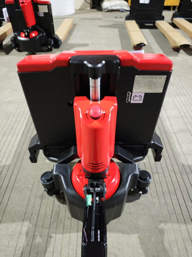 Top-down view from the operator end of the CBD20W-II showing the red emergency stop button on the drive motor cover, the handle linkage and the battery housing behind it